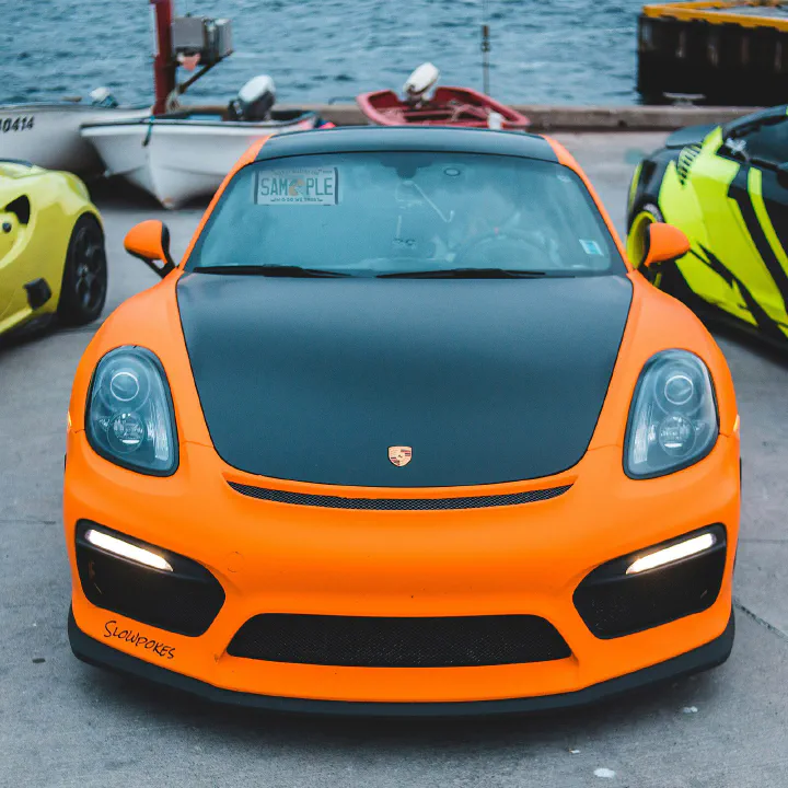 An orange Porsche Cayman with a sample plate behind the glass.